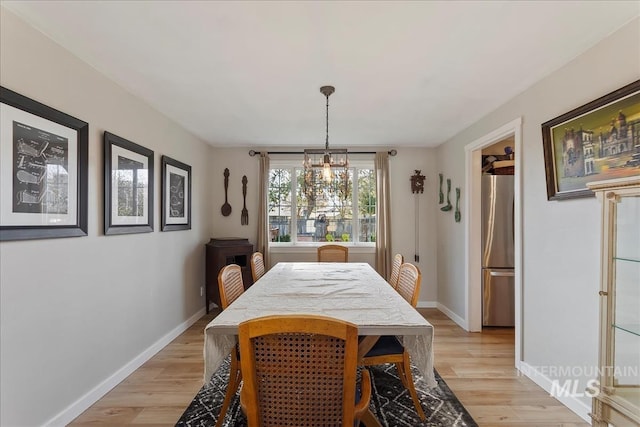 dining room with an inviting chandelier, light wood-style flooring, and baseboards