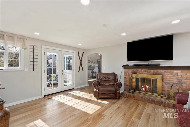 living area featuring light wood-style flooring, recessed lighting, baseboards, and arched walkways