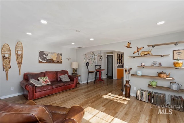 living area featuring recessed lighting, wood finished floors, arched walkways, and baseboards