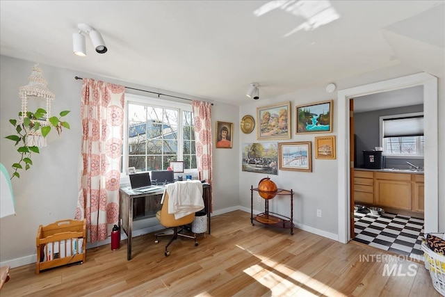 office featuring a sink, baseboards, and light wood finished floors