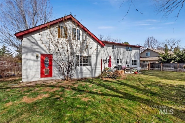 back of house with a fenced backyard and a yard