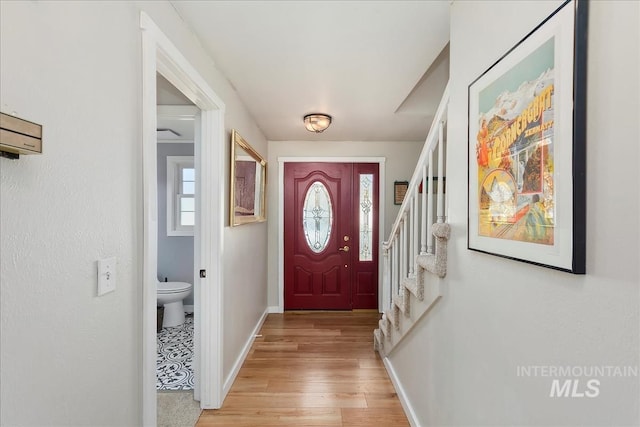 entrance foyer featuring stairway, light wood-style flooring, baseboards, and a wealth of natural light