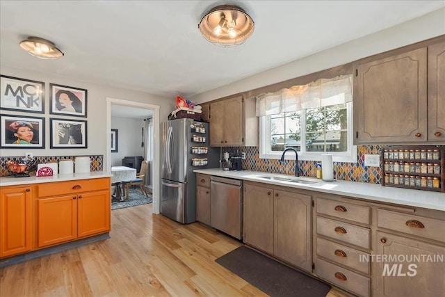 kitchen featuring appliances with stainless steel finishes, light wood-type flooring, light countertops, and a sink