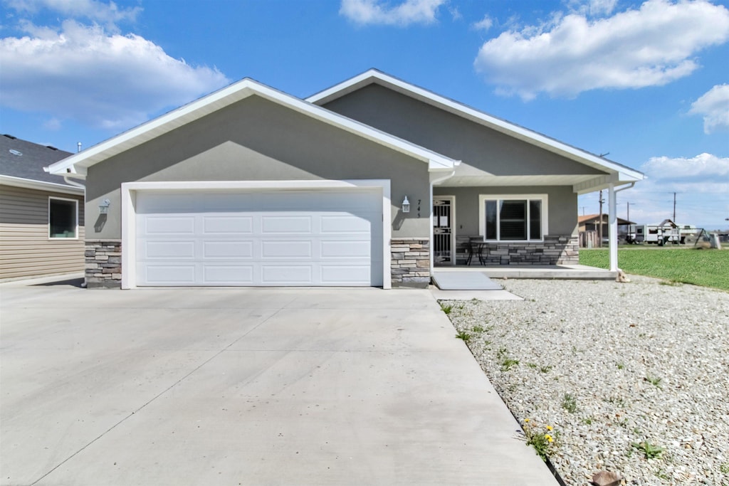 view of front of house featuring stucco siding, a garage, concrete driveway, and stone siding
