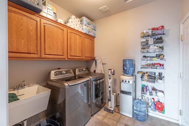 laundry room featuring sink, light tile patterned floors, cabinets, and independent washer and dryer