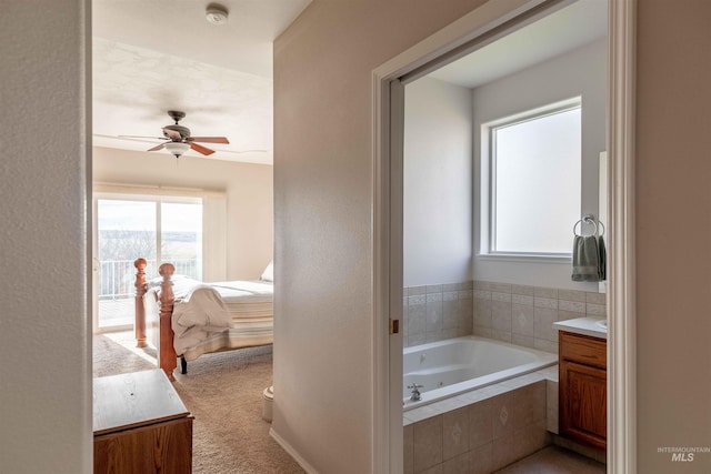 bathroom featuring vanity, tiled bath, plenty of natural light, and ceiling fan