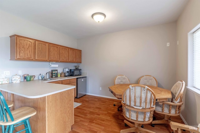 kitchen featuring kitchen peninsula, a breakfast bar, sink, light hardwood / wood-style flooring, and dishwasher