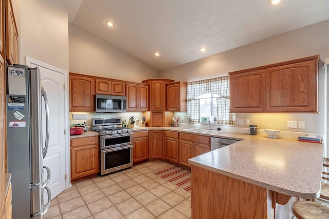 kitchen featuring sink, vaulted ceiling, appliances with stainless steel finishes, light tile patterned flooring, and kitchen peninsula