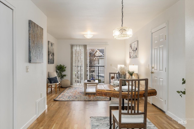 dining space with visible vents, light wood-type flooring, a chandelier, and baseboards