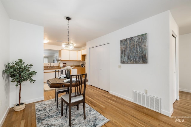 dining space featuring baseboards, visible vents, and light wood finished floors