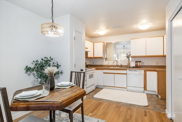 kitchen featuring decorative light fixtures, white appliances, light wood-style flooring, and a sink