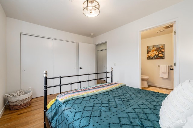 bedroom featuring visible vents, wood finished floors, connected bathroom, a closet, and baseboards