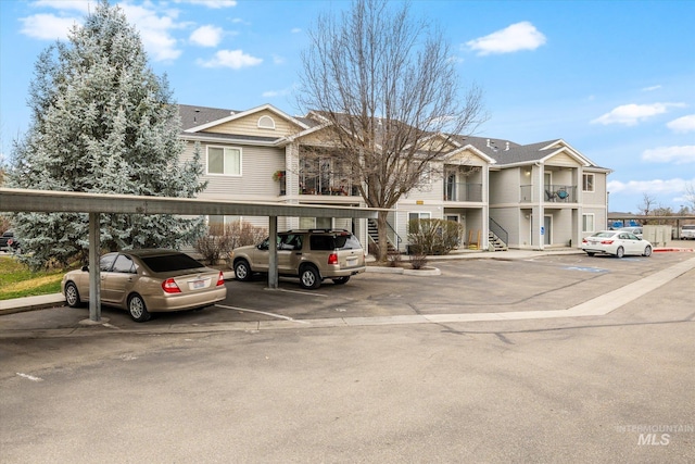 view of property featuring a residential view, stairs, and covered and uncovered parking