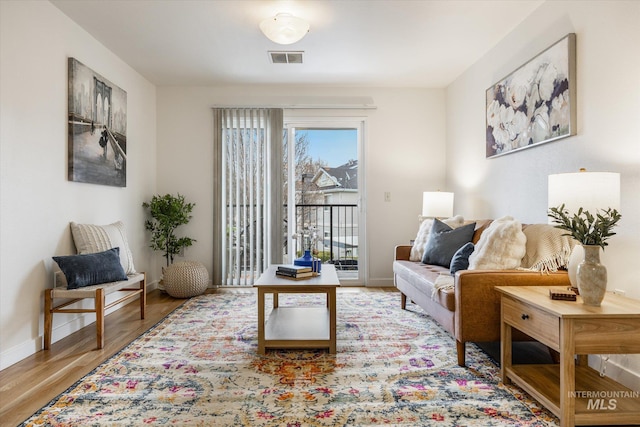 living area with visible vents, wood finished floors, and baseboards