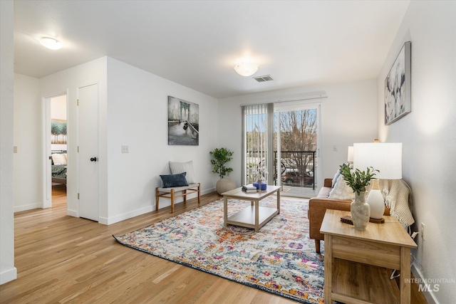 living room featuring visible vents, baseboards, and wood finished floors