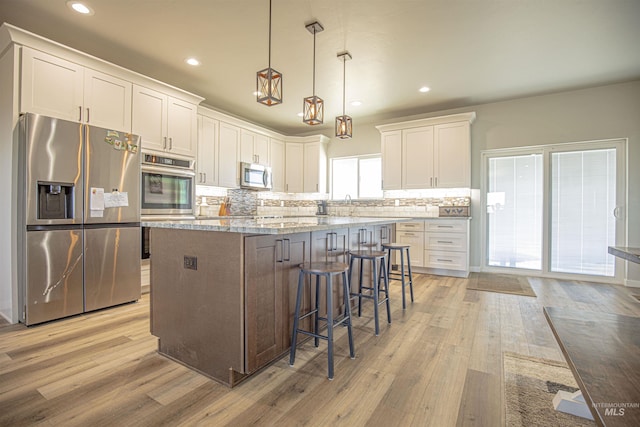 kitchen featuring hanging light fixtures, white cabinetry, appliances with stainless steel finishes, and a center island