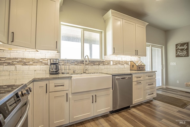 kitchen with light stone counters, stainless steel appliances, sink, and white cabinets