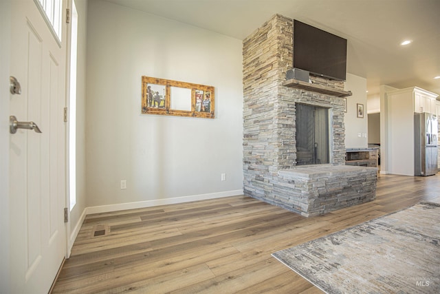 living room with a stone fireplace and light hardwood / wood-style floors