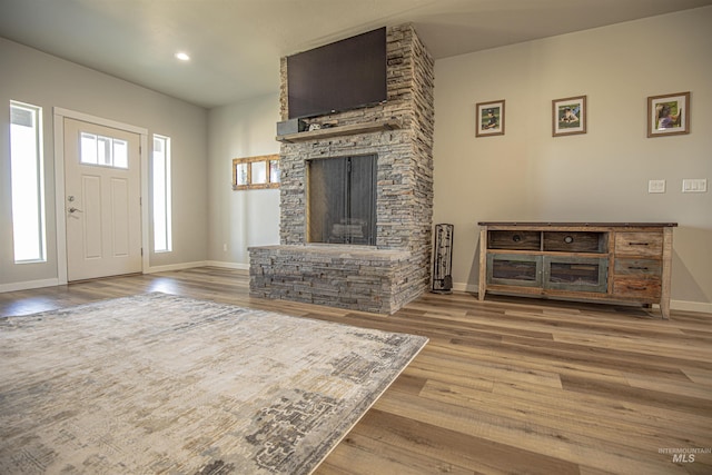 living room featuring wood-type flooring and a stone fireplace