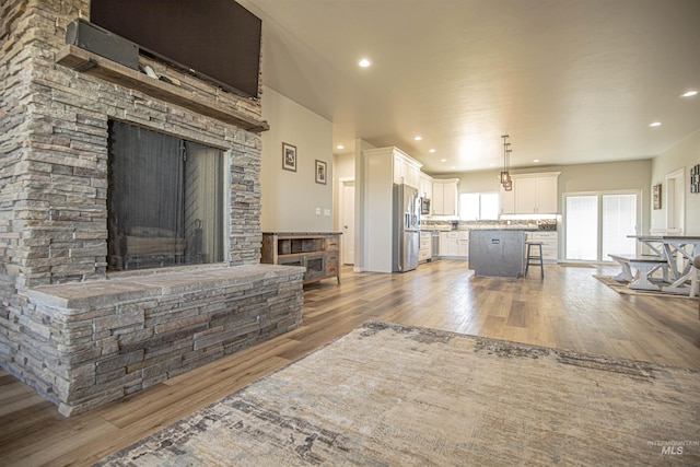 living room with a stone fireplace and light hardwood / wood-style floors