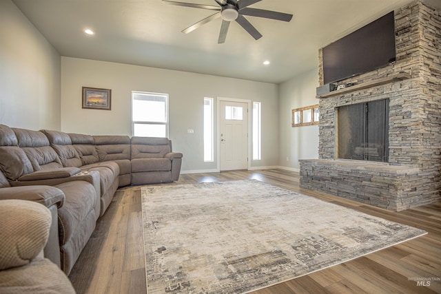 living room featuring a stone fireplace, hardwood / wood-style floors, and ceiling fan