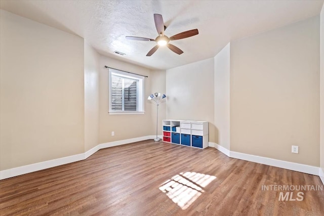 empty room featuring a textured ceiling, wood-type flooring, and ceiling fan