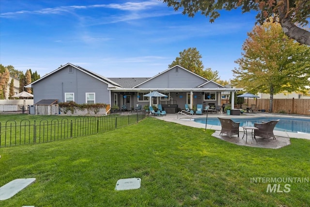 back of property featuring a fenced in pool, a patio area, and a lawn