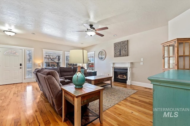 living room with hardwood / wood-style flooring, ceiling fan, and a textured ceiling