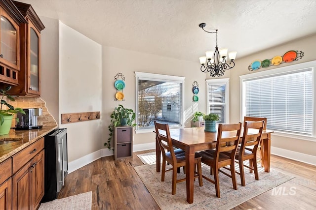 dining space featuring a notable chandelier, dark hardwood / wood-style floors, beverage cooler, and a textured ceiling