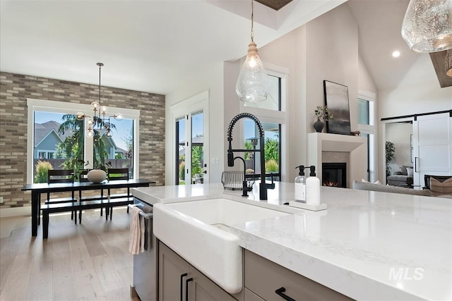 2685 N Fruniz Ave, Eagle, ID 83616 - kitchen featuring brick wall, light wood-style floors, pendant lighting, light stone countertops, and a glass covered fireplace