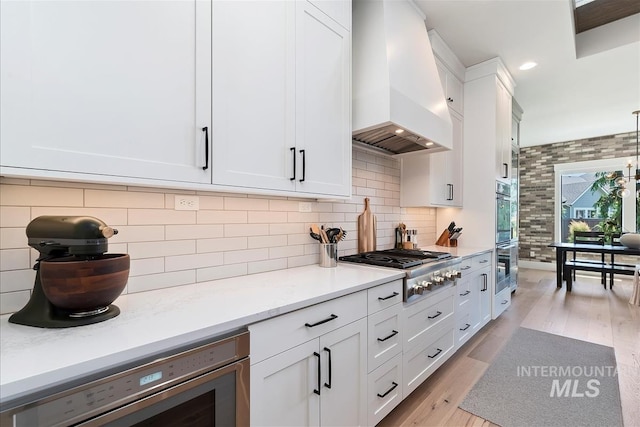 2685 N Fruniz Ave, Eagle, ID 83616 - kitchen with custom range hood, stainless steel gas cooktop, white cabinets, light wood-type flooring, and decorative backsplash