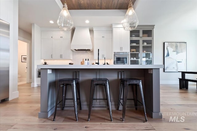 2685 N Fruniz Ave, Eagle, ID 83616 - kitchen with custom exhaust hood, oven, a breakfast bar area, recessed lighting, and backsplash