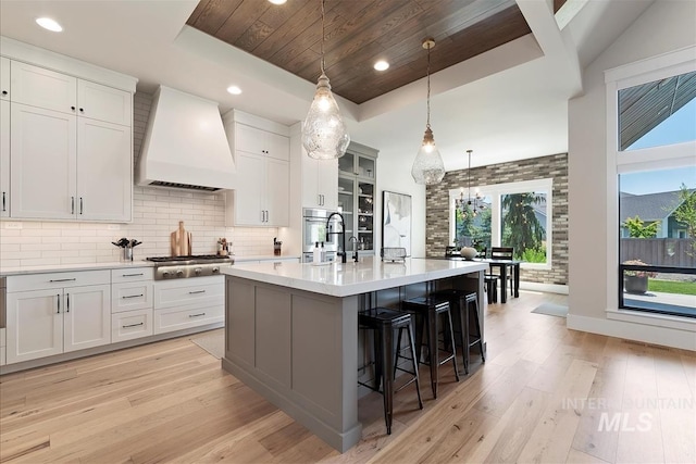 2685 N Fruniz Ave, Eagle, ID 83616 - kitchen featuring wall chimney range hood, appliances with stainless steel finishes, light wood-style flooring, light countertops, and white cabinets