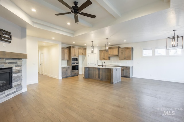 kitchen featuring hanging light fixtures, a center island with sink, light wood-type flooring, and stainless steel appliances