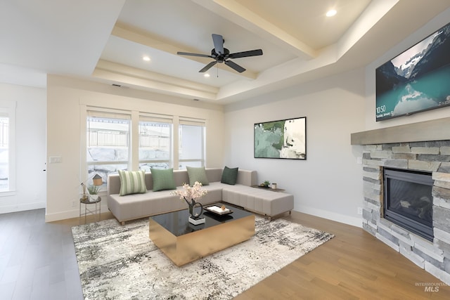 living room featuring a healthy amount of sunlight, a stone fireplace, and hardwood / wood-style floors