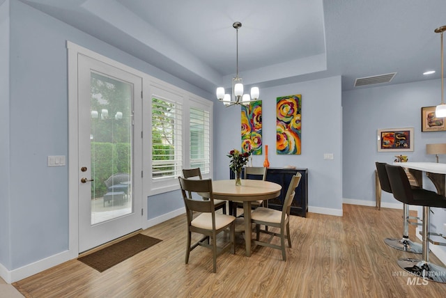 dining room with light hardwood / wood-style floors and an inviting chandelier