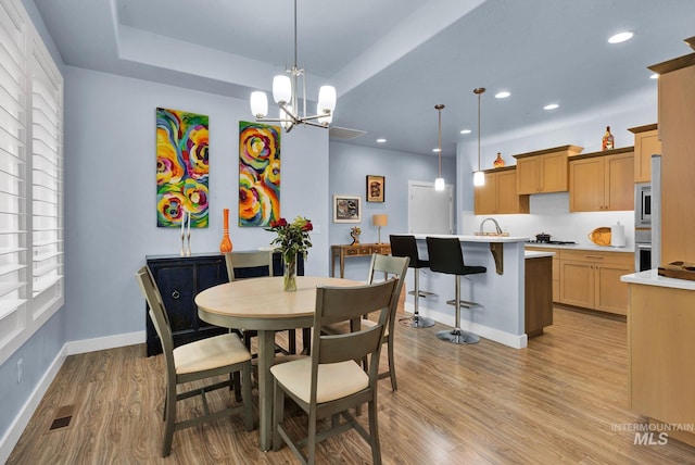 dining space with an inviting chandelier, light hardwood / wood-style floors, and sink