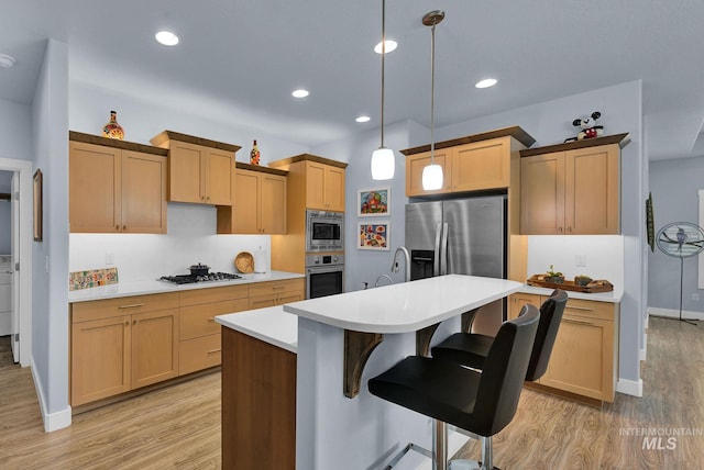 kitchen with light hardwood / wood-style floors, stainless steel appliances, an island with sink, and hanging light fixtures