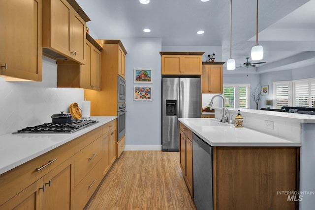 kitchen with stainless steel appliances, sink, decorative light fixtures, ceiling fan, and light wood-type flooring