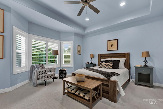 carpeted bedroom with a raised ceiling and ceiling fan