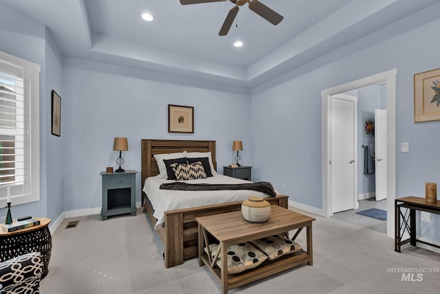 carpeted bedroom featuring ceiling fan and a tray ceiling