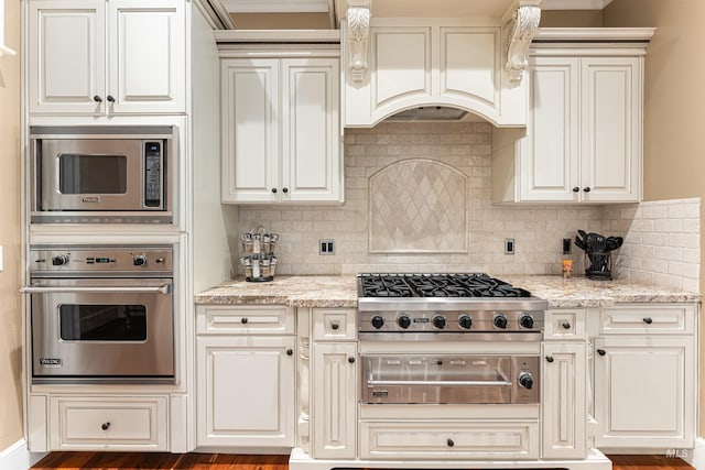 1137 N Cobblestone Way, Eagle, ID 83616 - kitchen with appliances with stainless steel finishes, tasteful backsplash, light stone counters, and custom range hood