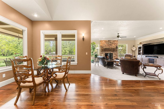 1137 N Cobblestone Way, Eagle, ID 83616 - dining area with a stone fireplace, wood finished floors, a ceiling fan, baseboards, and ornamental molding