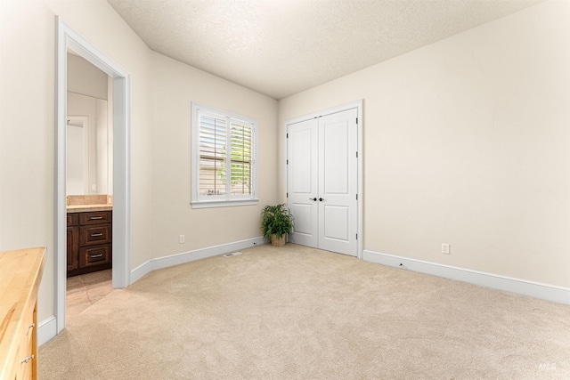 1137 N Cobblestone Way, Eagle, ID 83616 - unfurnished bedroom featuring light carpet, baseboards, a closet, a textured ceiling, and connected bathroom