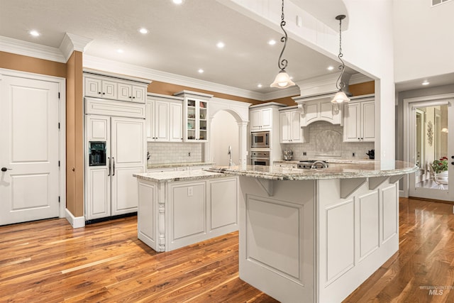 1137 N Cobblestone Way, Eagle, ID 83616 - kitchen with built in appliances, a large island with sink, recessed lighting, light wood-style flooring, and crown molding