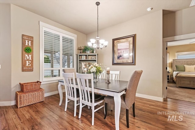 dining area with a chandelier, baseboards, and wood finished floors