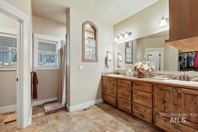 bathroom with double vanity, visible vents, baseboards, and a sink