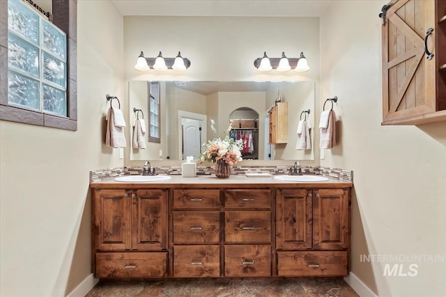 bathroom featuring double vanity, baseboards, and a sink