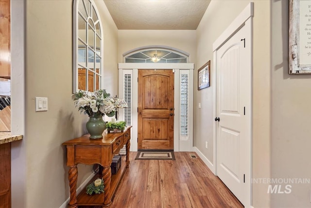 entryway with wood finished floors, baseboards, and a textured ceiling