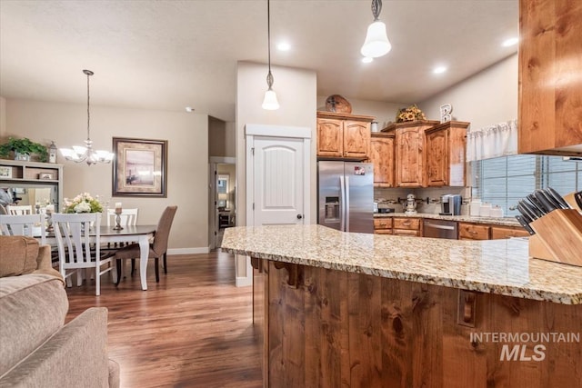 kitchen with light stone counters, dark wood finished floors, appliances with stainless steel finishes, and a peninsula